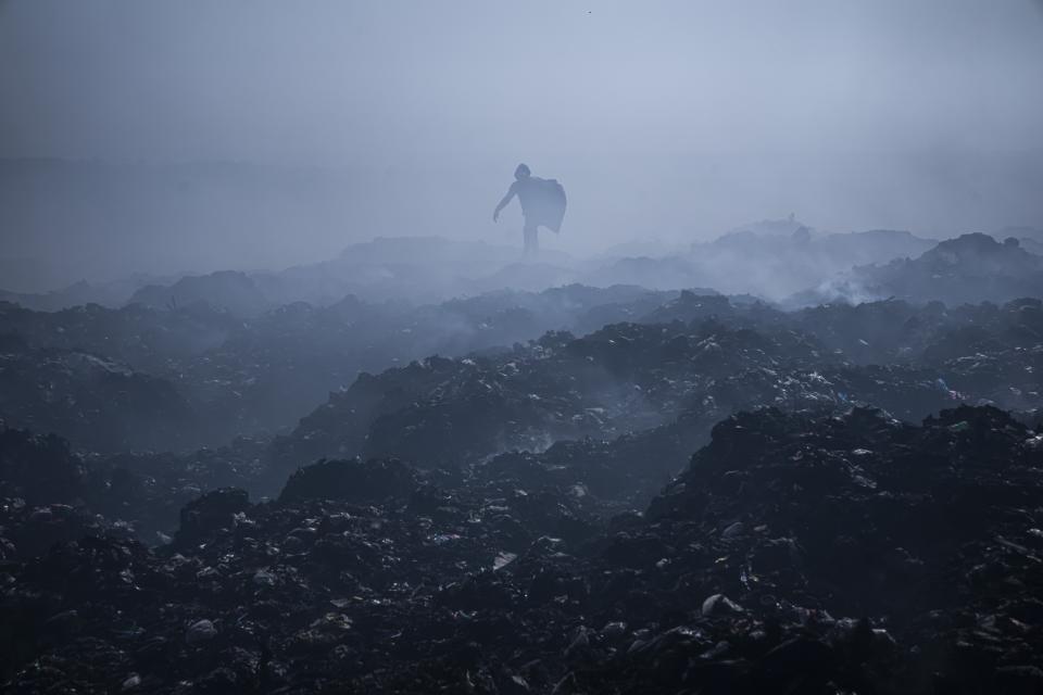 FILE - A Palestinian man collects plastic as smoke rises from a fire in a landfill, east of Gaza City, March 3, 2023. ] (AP Photo/Fatima Shbair, File)