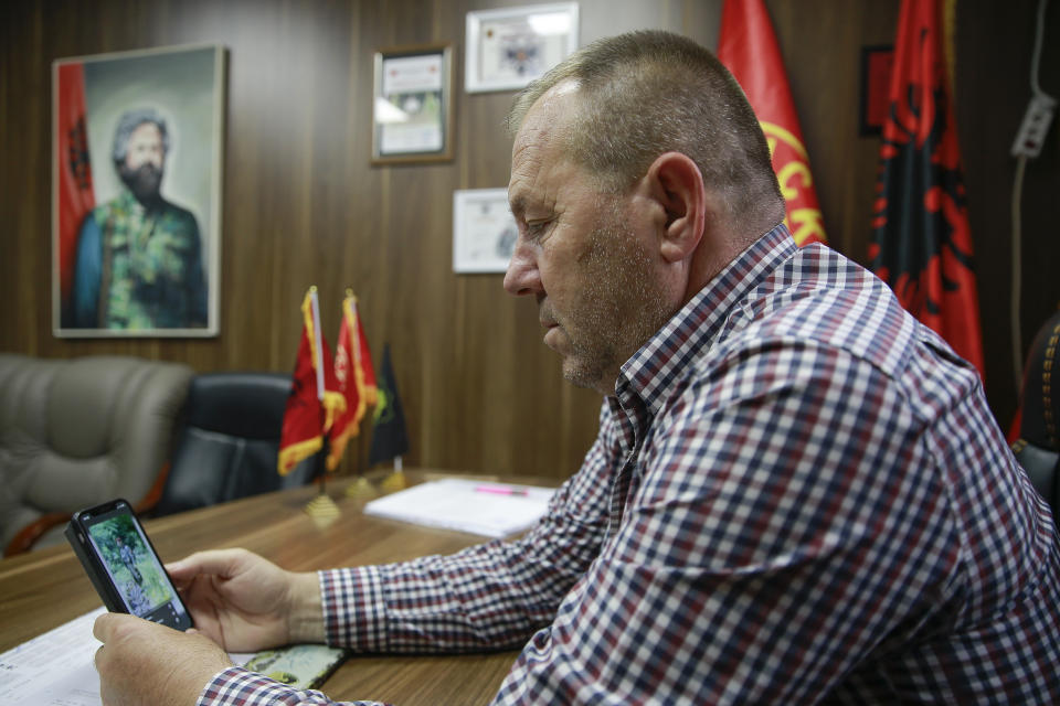 Hysni Gucati head of the War Veterans Organization of the Kosovo Liberation Army looks at a photo of his co-fighter former Kosovo Liberation Army commander Salih Mustafa after news of his arrest, during an interview with The Associated Press, in Pristina, Thursday, Sept. 24, 2020. A special international court said Thursday that a former commander of the separatist fighters in Kosovo's 1998-1999 war has been arrested as part of a war crimes and crimes against humanity probe stemming from the conflict with Serbia. (AP Photo/Visar Kryeziu)