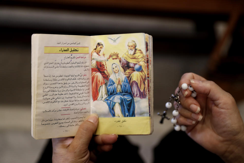 A Lebanese woman reads a religious book during Sunday Mass at Saint Maron-Baouchrieh Church that was damaged by last Tuesday's explosion that hit the Beirut seaport, in Baouchrieh neighborhood in Beirut, Lebanon, Sunday, Aug. 9, 2020. In interviews with The Associated Press, Father Rabih Thoumy and church priest Father Marwan Mouawad recount the horror of the moment the blast rocked the church. Thoumy says: "God has saved us.” (AP Photo/Hussein Malla)