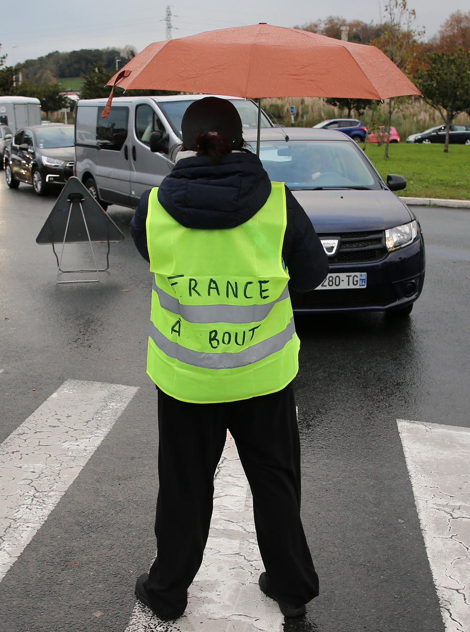 A demonstrator wears a jacket that reads: "France is Exhausted" as he block cars in Bayonne, southwestern France, Sunday, Nov. 18, 2018. One protester was killed and 227 other people were injured — eight seriously — at roadblocks set up around villages, towns and cities across France on Saturday as citizens angry with rising fuel taxes rose up in a grassroots movement, posing a new challenge to beleaguered President Emmanuel Macron. (AP Photo/Bob Edme)