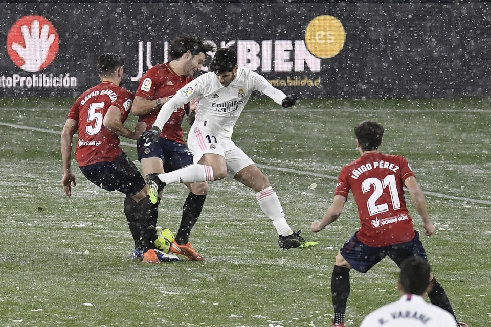 Marco Asensio, del Real Madrid, disputa un balón con David García, del Osasuna, durante un encuentro disputado bajo una nevad en Pamplona, España, el sábado 9 de enero de 2021 (AP foto/Alvaro Barrientos)