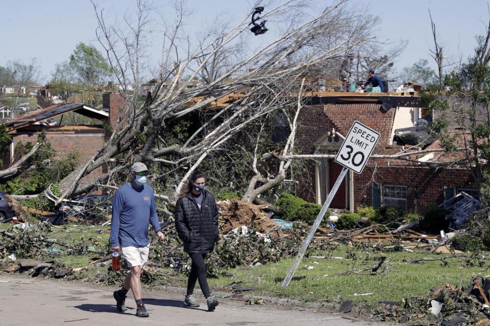 People walk up a street of damaged homes Tuesday, April 14, 2020, in Chattanooga, Tenn. Tornadoes went through the area Sunday, April 12. (AP Photo/Mark Humphrey)