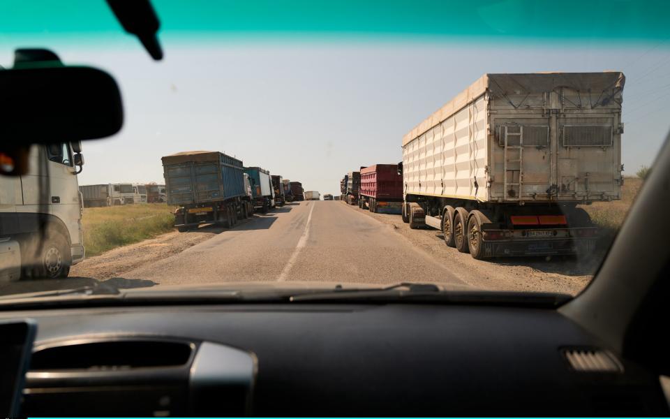 Trucks containing grain line up on the side of the road in Reni, Ukraine