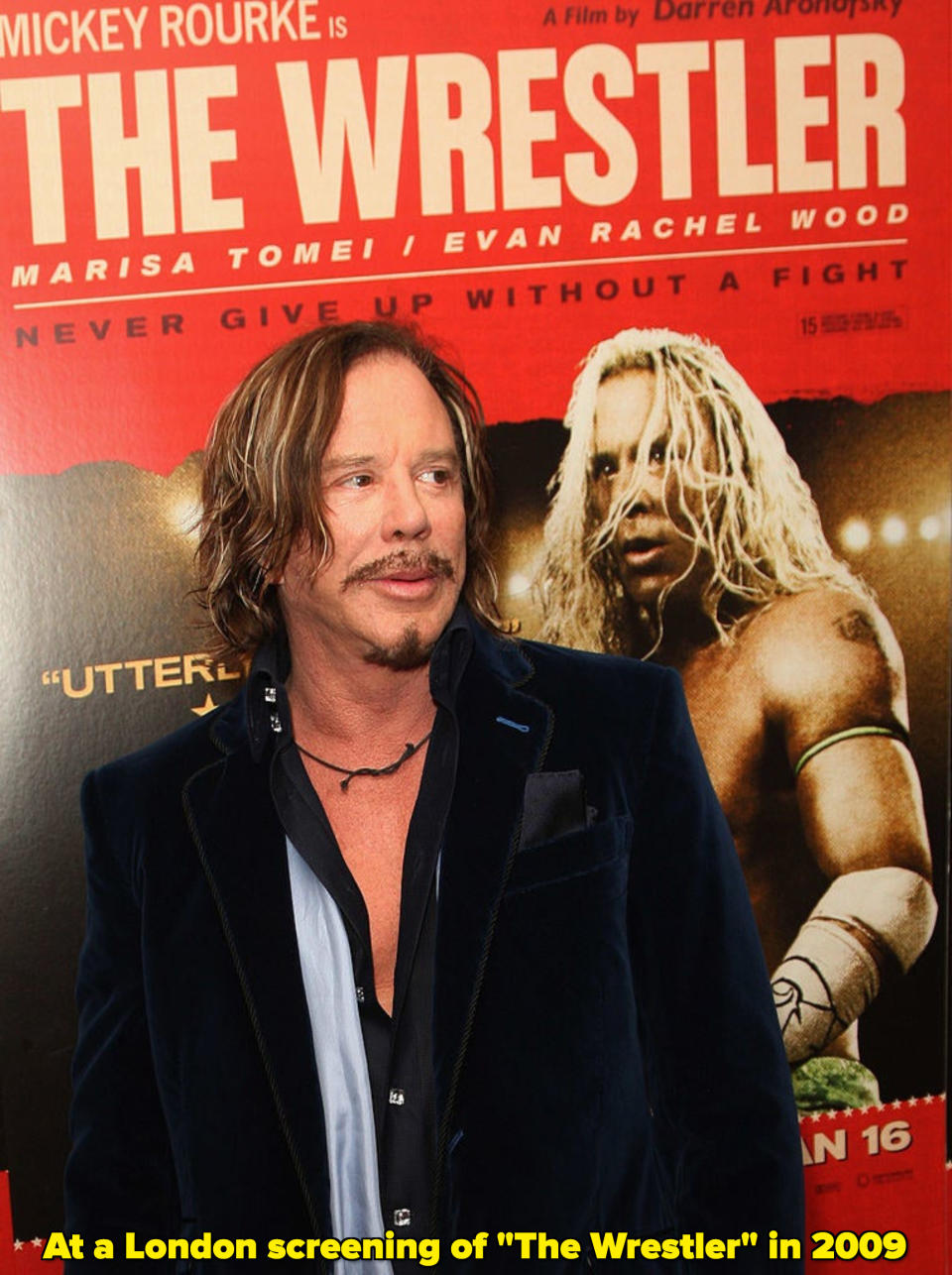 Mickey Rourke standing by a poster for "The Wrestler"