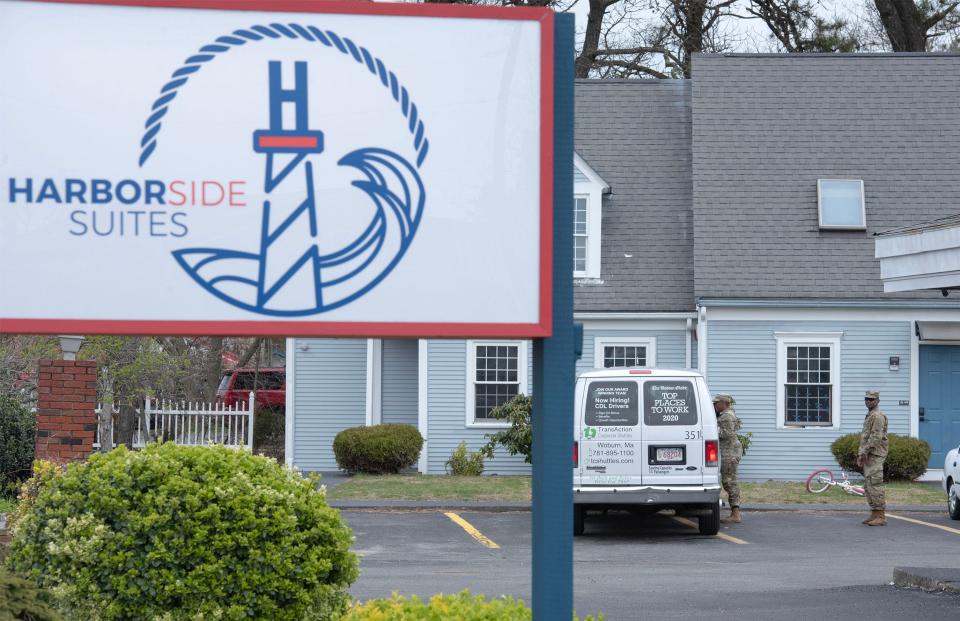 A pair of Massachusetts National Guard members talk to a transport van driver Wednesday at Harborside Suites on Route 28 in South Yarmouth, part of transportation arrangements for state sheltered families moving to off-Cape sites.