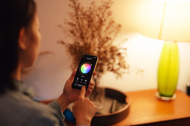 Woman using smartphone to adjust a smart light (Photo: Getty)