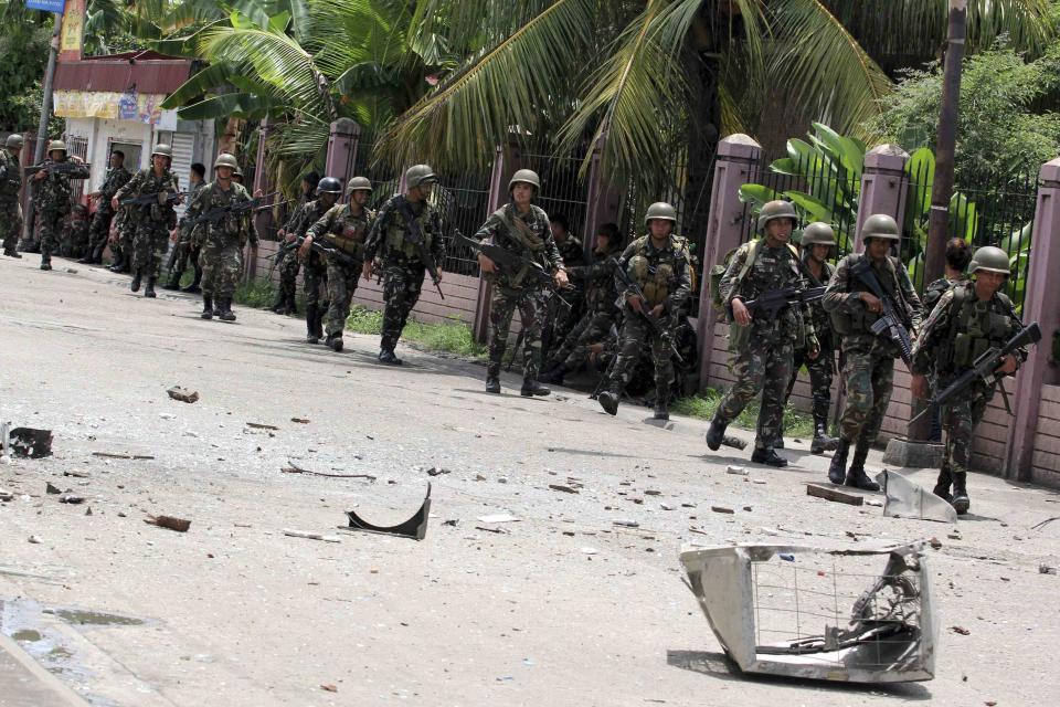 Security forces walks past debris scattered on a street after rebels from the Moro National Liberation Front (MNLF) clashed with government troops in Zamboanga city