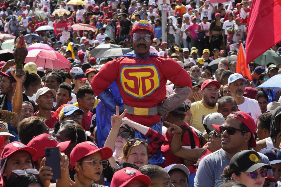 Un seguidor disfrazado de "Súper Bigote", un personaje de dibujos animados que muestra al presidente Nicolás Maduro como un superhéroe, entre la multitud que asistió a un acto de campaña previo a las elecciones presidenciales, en Caracas, Venezuela, el 18 de julio de 2024. (AP Foto/Ariana Cubillos)