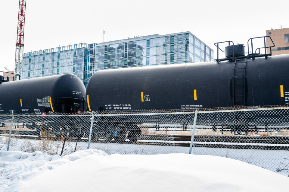 Tank Railcars in a Snowy Cargo Train Terminal with Buildings in Background. Calgary, AB, Canada.