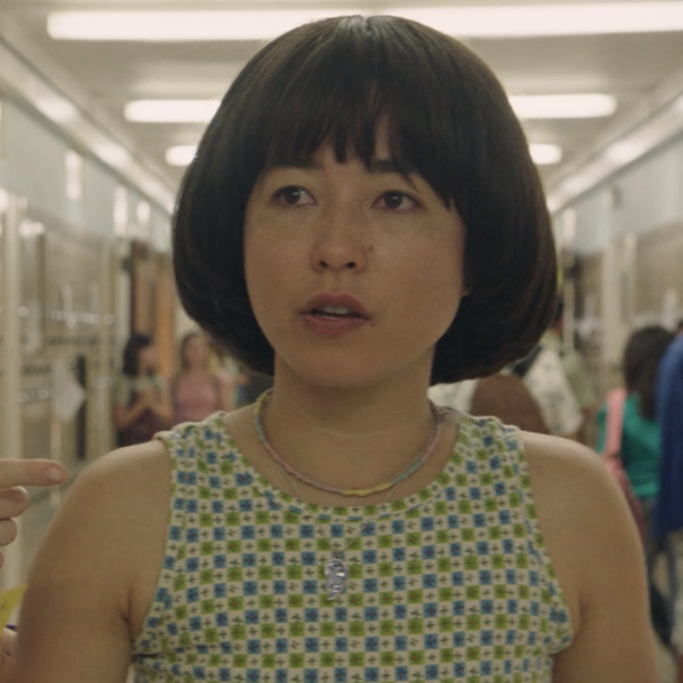 Maya in a scene with a brightly colored tanktop, necklace, and hair in a bob