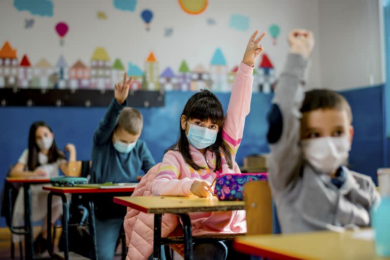 Elementary schoolchildren wearing a protective face masks  in the classroom. Education during epidemic.