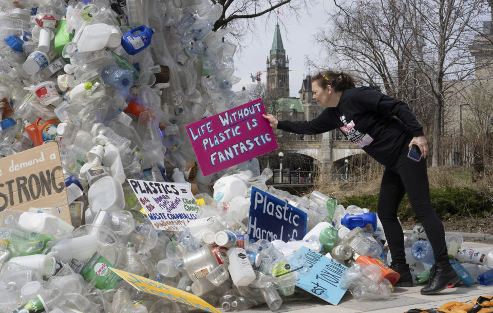 FILE - Activist Dianne Peterson places a sign on an art installation outside a United Nations conference on plastics, April 23, 2024, in Ottawa, Ontario. (Adrian Wyld/The Canadian Press via AP. File)