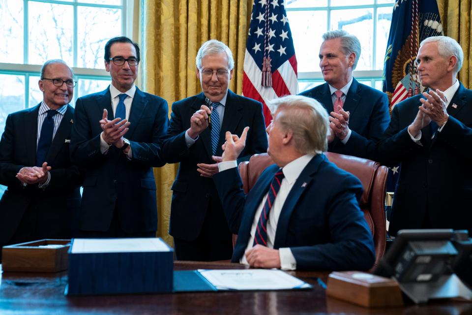 President Donald Trump hands a pen to Senate Majority Leader Mitch McConnell of Ky., after signing the coronavirus stimulus relief package in the Oval Office at the White House, Friday, March 27, 2020, in Washington. From left, White House chief economic adviser Larry Kudlow, Treasury Secretary Steven Mnuchin, McConnell, Trump, House Minority Leader Kevin McCarty, R-Calif., and Vice President Mike Pence. (AP Photo/Evan Vucci)