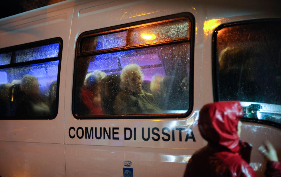 Elderly residents sit in a bus in Ussita