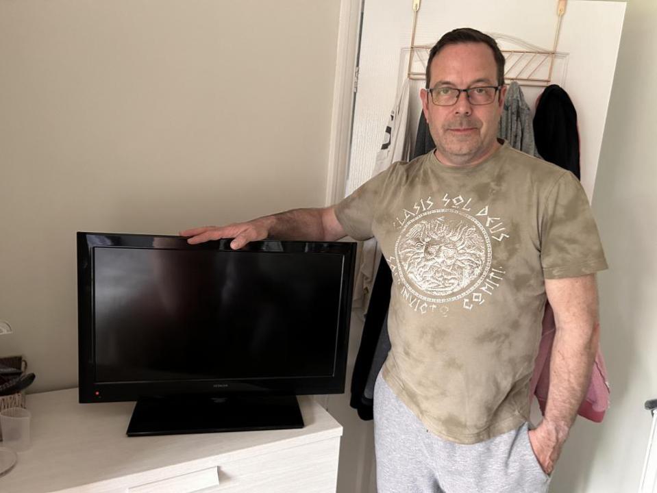 York Press: Thrifty dad Darren Leeming, 54, with a TV he picked up from Facebook Marketplace. Picture: SWNS