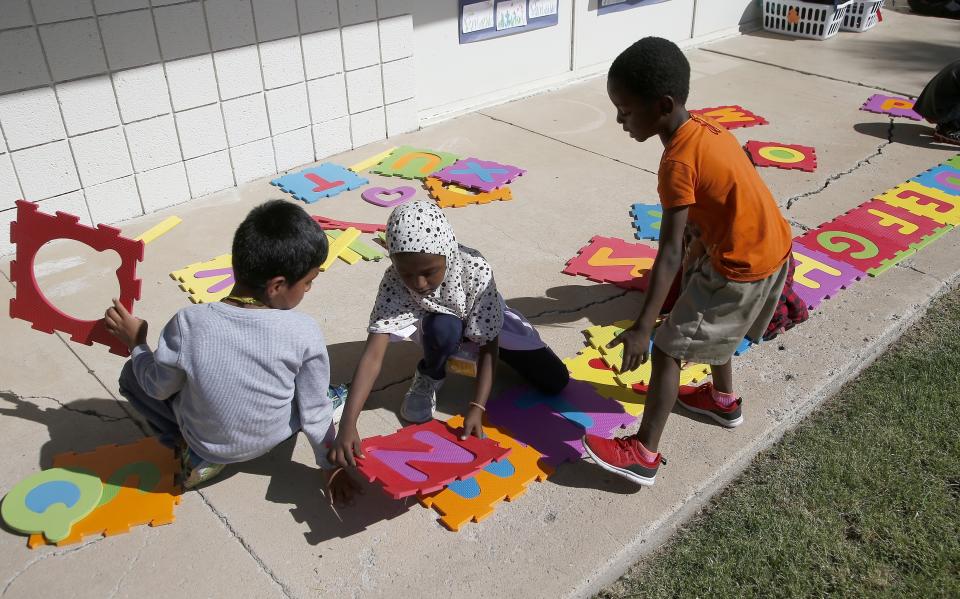 Students Oscar Sobrevilla, left, Kediga Ahmend, middle, and Honore Alimasi, right, work on their alphabet at Valencia Newcomer School Thursday, Oct. 17, 2019, in Phoenix. Children from around the world are learning the English skills and American classroom customs they need to succeed at so-called newcomer schools. Valencia Newcomer School in Phoenix is among a handful of such public schools in the United States dedicated exclusively to helping some of the thousands of children who arrive in the country annually. (AP Photo/Ross D. Franklin)