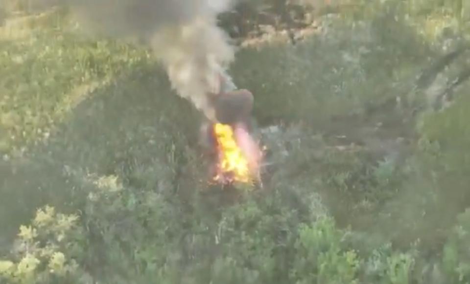 A screenshot from a video of a Russian T-90 tank falling off a cliff and being destroyed by Ukrainian attack drones.