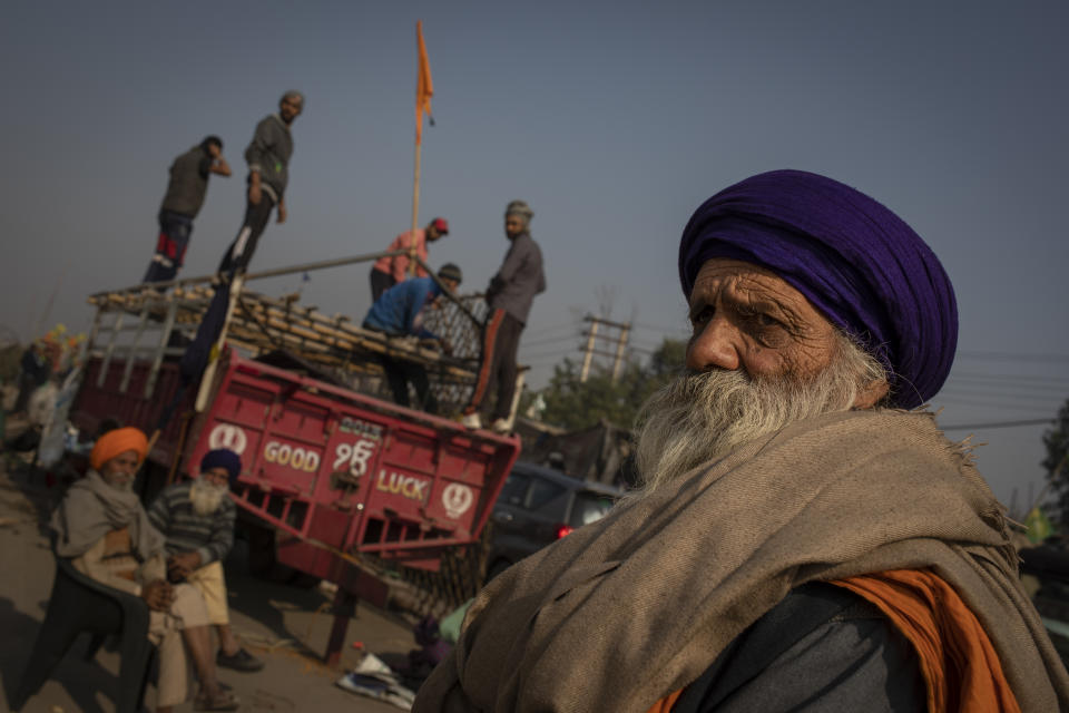 An elderly Sikh farmer looks on as others dismantle temporary structures used during protests in Singhu, on the outskirts of New Delhi, India, Saturday, Dec. 11, 2021. Tens of thousands of jubilant Indian farmers on Saturday cleared protest sites on the capital's outskirts and began returning home, marking an end to their year-long demonstrations against agricultural reforms that were repealed by Prime Minister Narendra Modi's government in a rare retreat. (AP Photo/Altaf Qadri)