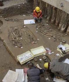 Personas excavando esqueletos humanos en la tierra.
