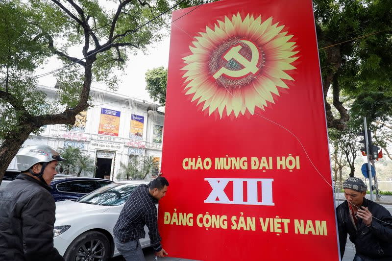 Workers set up a poster for upcoming 13th National Congress of the ruling Communist Party of Vietnam, on a street in Hanoi