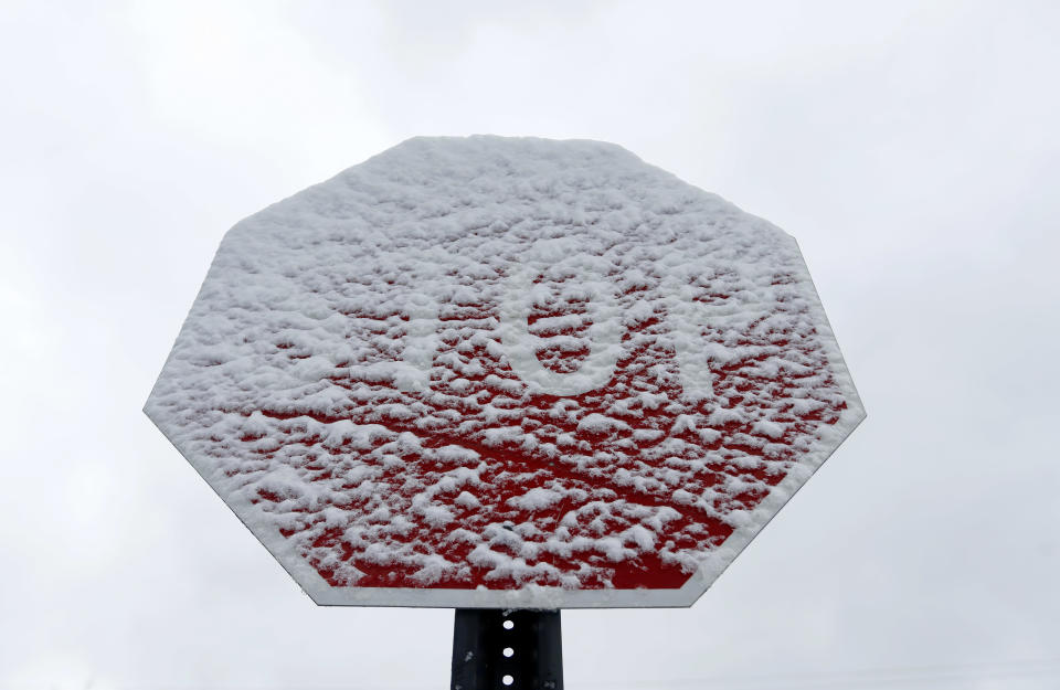 A stop sign is covered in snow in Detroit, Tuesday, April 15, 2014. A spring storm left roads slippery across Michigan and shattered seasonal snowfall records in Detroit and Flint. (AP Photo/Paul Sancya)