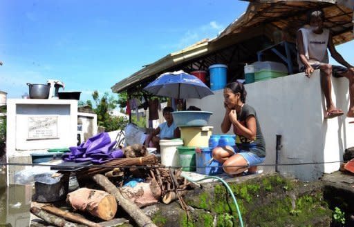 A Philippine mother-of-two talks on her mobile phone as she crouches on top of a tomb that has served as her family's temporary home in Calumpit since August 8. As floods which have swamped parts of the Philippines and affected more than two million people extend into their second week, the dead and the living are sharing premium space on dry ground