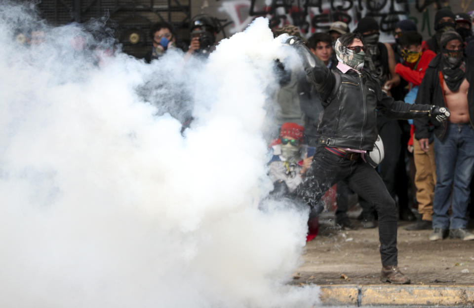 A demonstrator throws a tear gas canister back at police during an anti-government protest in Santiago, Chile, Monday, Nov. 4, 2019. Chile has been facing weeks of unrest, triggered by a relatively minor increase in subway fares. The protests have shaken a nation noted for economic stability over the past decades, which has seen steadily declining poverty despite persistent high rates of inequality. (AP Photo/Esteban Felix)