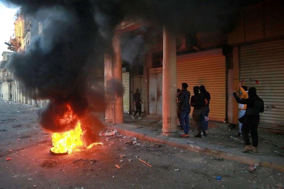 Riot police fire tear gas while protesters set fires during clashes between Iraqi security forces and anti-Government protesters in Baghdad, Iraq, Thursday, Nov. 21, 2019. Iraqi officials said several protesters killed as heavy clashes erupt in central Baghdad. (AP Photo/Khalid Mohammed)