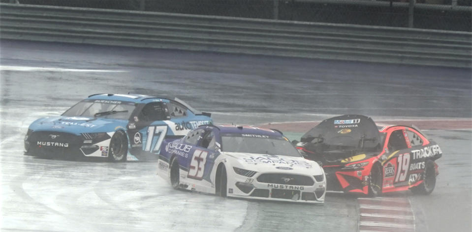 Martin Truex Jr. (19) slides through Turn 12 after a crash as Chris Buescher (17) and Garrett Smithley (53) drive around during the NASCAR Cup Series auto race at the Circuit of the Americas in Austin, Texas, Sunday, May 23, 2021. (AP Photo/Chuck Burton)