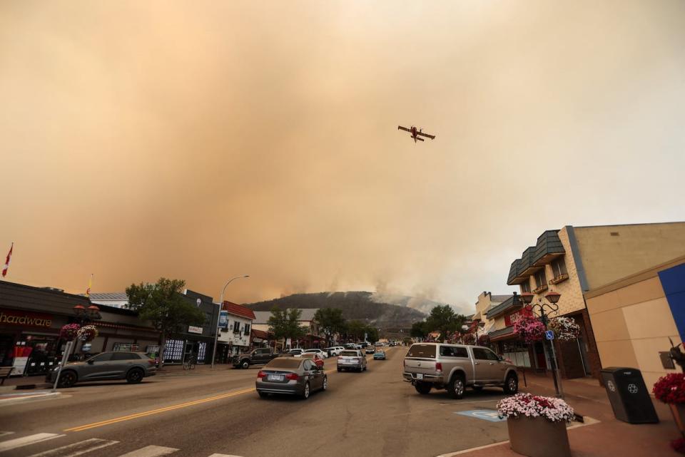 A water bomber flies over the Eagle Bluff wildfire, after it crossed the Canada-U.S. border from the state of Washington and prompted evacuation orders, in Osoyoos, B.C. on July 30, 2023. 