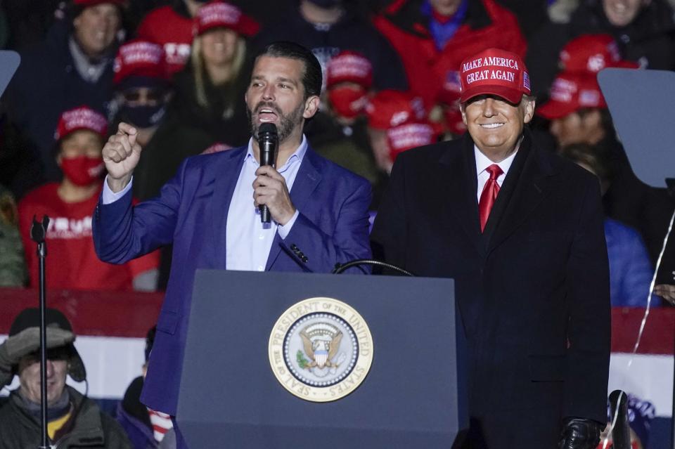 FILE - In this Nov. 2, 2020, file photo President Donald Trump watches as Donald Trump Jr. speaks at a campaign event at the Kenosha Regional Airport in Kenosha, Wis. A spokesman says President Donald Trump’s eldest son, Donald Trump Jr., has been infected with the coronavirus. The spokesman says the younger Trump learned his diagnosis earlier this week, has no symptoms and has been quarantining. (AP Photo/Morry Gash, File)