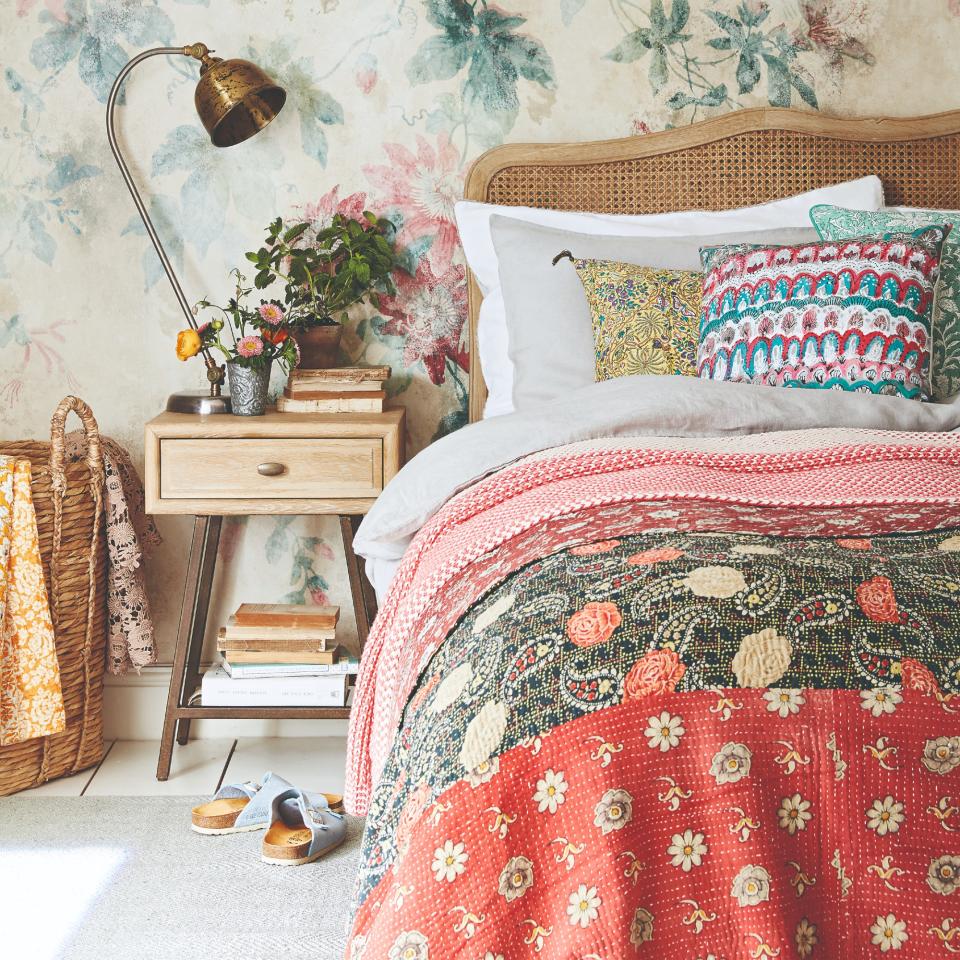 A Bohemian-style bedroom with patterned bedding and floral wallpaper