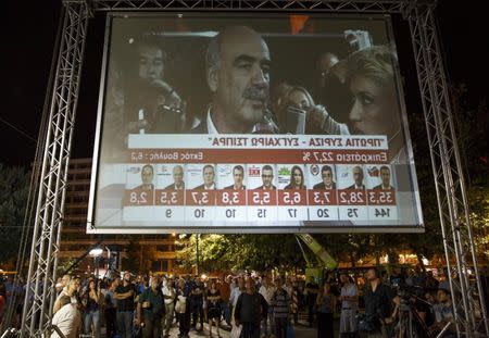 People look at the results of exit polls on a giant screen as the leader of the conservative New Democracy party Vangelis Meimarakis is interviewed on television after polls closed in a general election in Athens, Greece, September 20, 2015. REUTERS/Paul Hanna