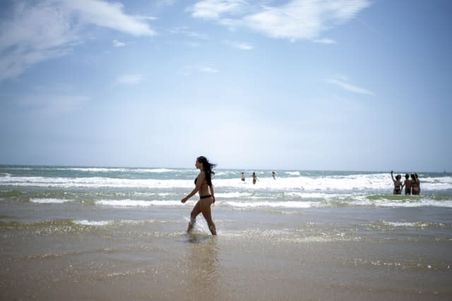 A woman enjoys the cool sea water in the sunshine on the beach in Bournemouth, Dorset 