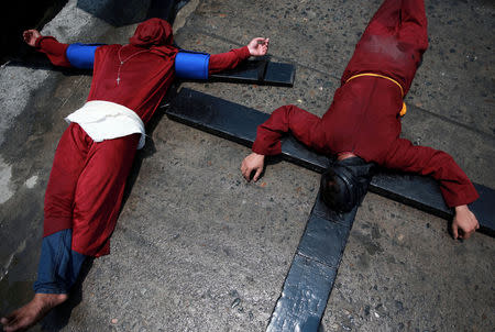 Filipino penitents bearing crosses on their backs lie on the street as they perform a ritual on Maundy Thursday in Mabalacat City, Pampanga province, Philippines, April 18, 2019. REUTERS/Eloisa Lopez