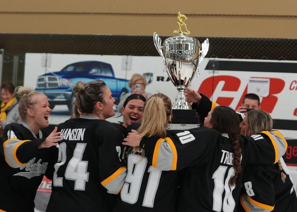 Adrian College lifts up the Slaats Cup after winning Saturday's game against St. Norbert.