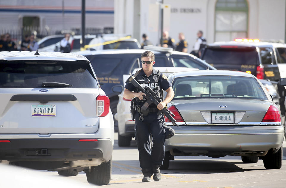 A Tucson Police Department officer walks with his weapon near the scene of a shooting aboard an Amtrak train in downtown Tucson, Ariz., Monday, Oct. 4, 2021. One person is in custody after someone opened fire Monday aboard an Amtrak train in Tucson, Arizona, police said. The shooting happened just after 8 a.m. on a train parked at the station in the city's downtown. Authorities say the scene has been secured and no threat remains. (Mamta Popat/Arizona Daily Star via AP)