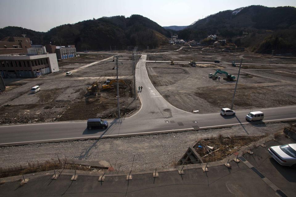 In this Feb. 22, 2012, file photo, two officials walk along a street in the tsunami and earthquake destroyed town of Onagawa, Miyagi Prefecture, northern Japan. (AP Photo/David Guttenfelder, File)