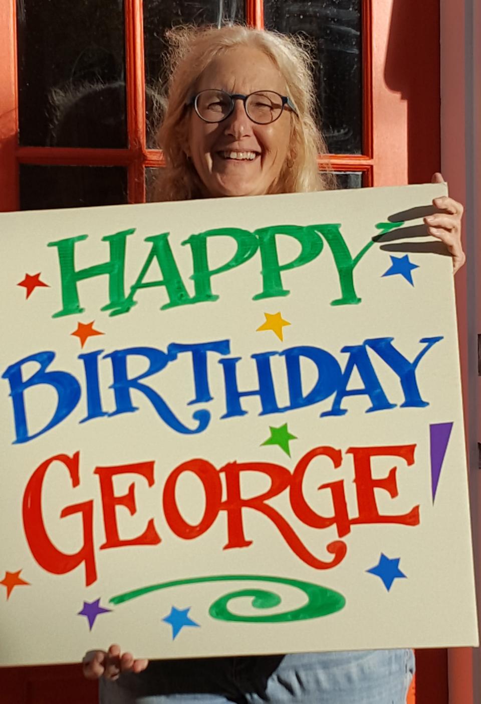 Nan Parati has been making signs for the Newport Folk and Jazz festivals since 1992. She's shown holding a sign she made for George Wein's 95th birthday in 2020.