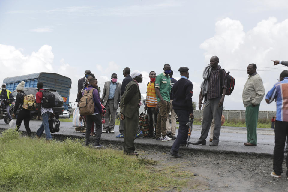 A Kenyan police officer speaks to people at a road block along Mombasa Road after vehicles traveling to Mombasa and Machakos were turned away, in Nairobi, Kenya, Tuesday, April 7, 2020. Kenya increased its restrictions to combat the coronavirus, announcing travel bans into and out of the capital city, Nairobi, the port of Mombasa and two counties. More than half of Africa’s 54 countries have imposed lockdowns, curfews, travel bans or other restrictions to try to contain the spread of COVID-19. (AP Photo/Khalil Senosi)