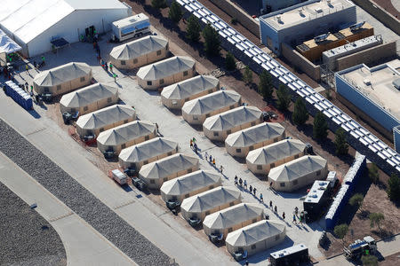 Immigrant children, many of whom have been separated from their parents under a new "zero tolerance" policy by the Trump administration, walk in single file between tents in their compound next to the Mexican border in Tornillo, Texas, U.S. June 18, 2018. REUTERS/Mike Blake