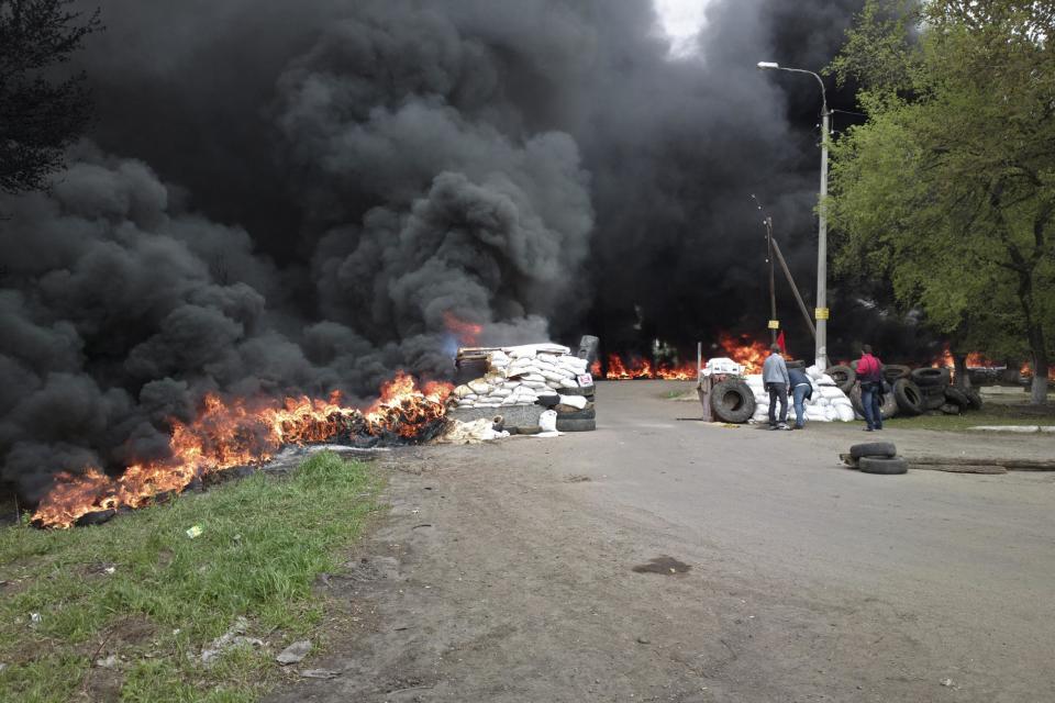 Black smoke billows from burning tires at a checkpoint following an attack by Ukrainian troops outside Slovyansk, Ukraine, Thursday, April 24, 2014. Ukrainian government troops moved against pro-Russia forces in the east of the country on Thursday and killed at least two of them in clashes at checkpoints manned by the insurgents, the government and insurgents said. Russian President Vladimir Putin decried what he described as a "punitive operation." (AP Photo/Mika Velikovskiy)