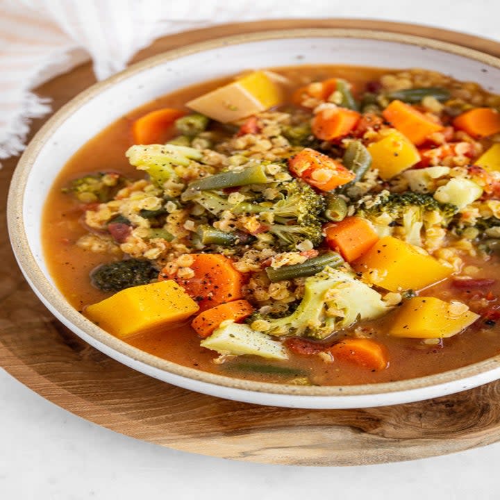 a bowl with quinoa, broth, and a variety of vegetables in it