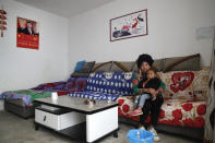 A minority Yi woman and her child sit inside her house displaying a poster of Chinese President Xi Jinping, left, in Xujiashan village in Ganluo County, southwest China's Sichuan province on Sept. 10, 2020. Communist Party Xi’s smiling visage looks down from the walls of virtually every home inhabited by members of the Yi minority group in a remote corner of China’s Sichuan province. Xi has replaced former leader Mao Zedong for pride of place in new brick and concrete homes built to replace crumbling traditional structures in Sichuan’s Liangshan Yi Autonomous Prefecture, which his home to about 2 million members of the group. (AP Photo/Andy Wong)