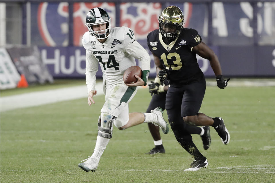 Michigan State quarterback Brian Lewerke (14) runs away from Wake Forest defensive lineman Manny Walker (13) during the second half of the Pinstripe Bowl NCAA college football game Friday, Dec. 27, 2019, in New York. (AP Photo/Frank Franklin II)