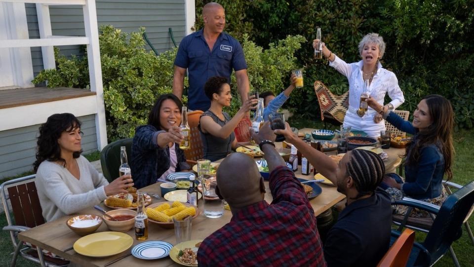 The Fast X cast at a picnic table toasting during a barbecue 