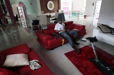 Vigilante known as "El Love" looks at several mobile phones while sitting in the living room of the house of a top leader of the Caballeros Templarios, or Knights Templar, in Nueva Italia January 16, 2014. REUTERS/Jorge Dan Lopez/Files