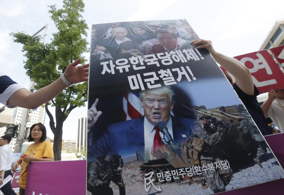 A protester carries a board during a rally to oppose a joint military exercise between South Korea and the United States near the U.S. embassy in Seoul, South Korea, Tuesday, Aug. 6, 2019. North Korea on Tuesday continued to ramp up its weapons demonstrations by firing unidentified projectiles twice into the sea while lashing out at the United States and South Korea for continuing their joint military exercises that the North says could derail fragile nuclear diplomacy. The sign reads "The withdrawal of the U.S. troops." (AP Photo/Ahn Young-joon)