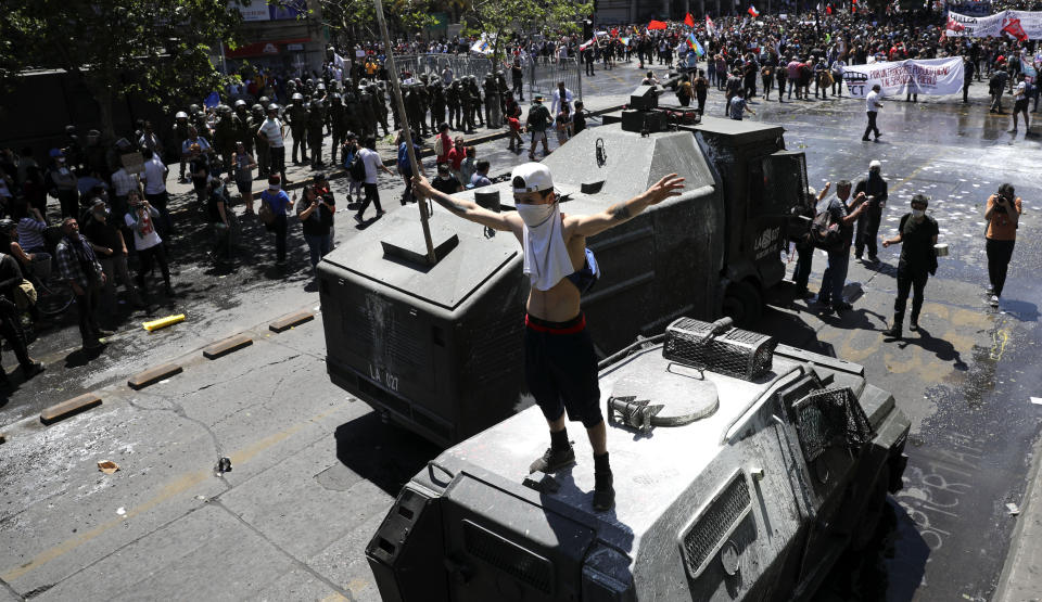 A demonstrator stands on a police armored vehicle during a protest in Santiago, Chile, Wednesday, Oct. 23, 2019. Rioting, arson attacks and violent clashes wracked Chile as the government raised the death toll to 15 in an upheaval that has almost paralyzed the South American country long seen as the region's oasis of stability. (AP Photo/Rodrigo Abd)