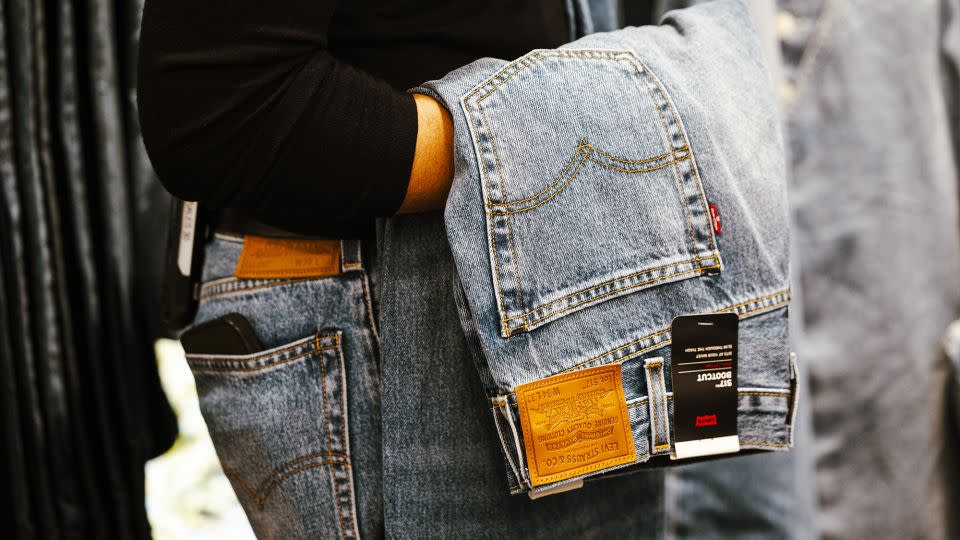 A worker carries a pair of jeans inside a Levi's store in New York, US, on Thursday, March 7, 2024. - Angus Mordant/Bloomberg/Getty Images